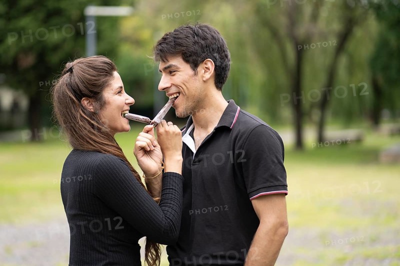 Young couple in love eating a popsicle in the park
