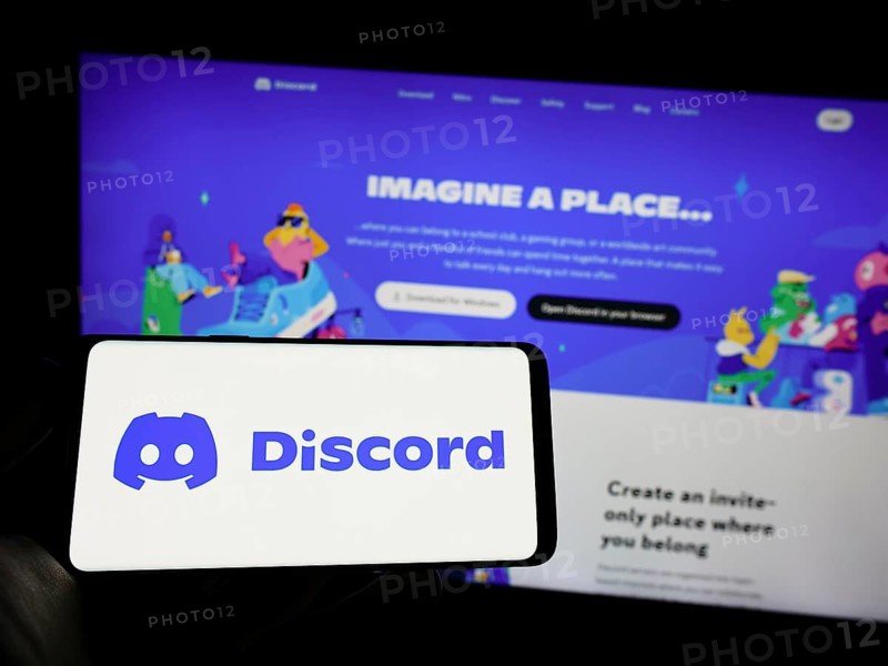 Stuttgart, Germany, 03-25-2023: Person holding mobile phone with logo of American social network company Discord Inc. on screen in front of web page. Focus on phone display, Europe