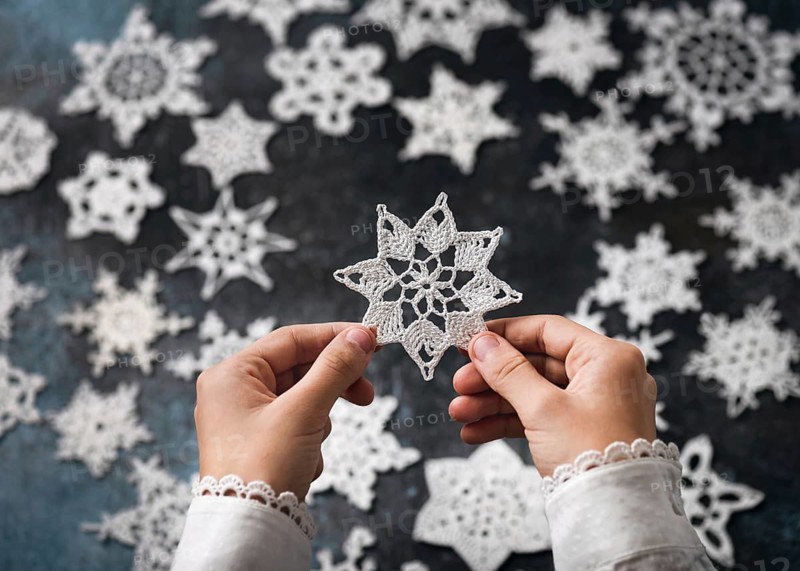 A crocheted snowflake, star made of white cotton in the girl's hands as a small handmade Christmas gift or home decoration. Hobby and handicraft concept