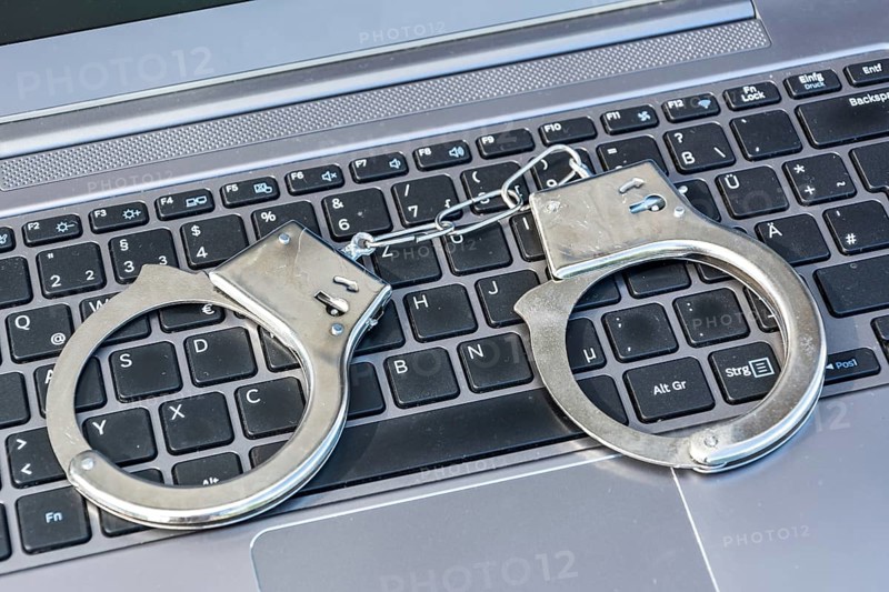 Handcuffs lying on computer keyboard as a symbol for cybercrime