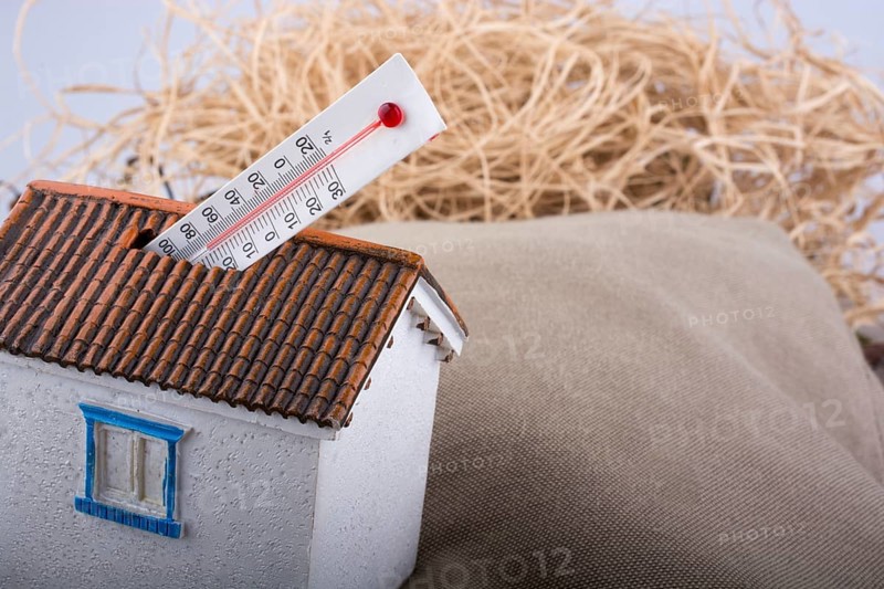 Thermometer measuring high temperature placed on a little model house