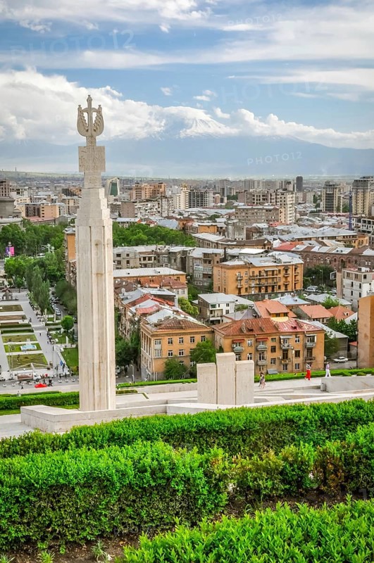 Photo of large monument surrounded by greenery and buildings of capital city Yerevan in Armenia