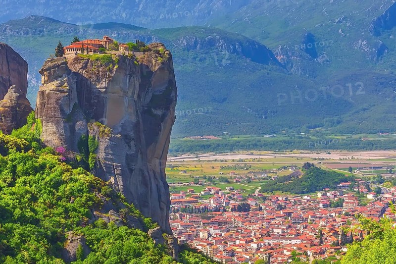 Holy Trinity Monastery on cliff rock top, Meteora, Greece and Kalampaka town in the valley
