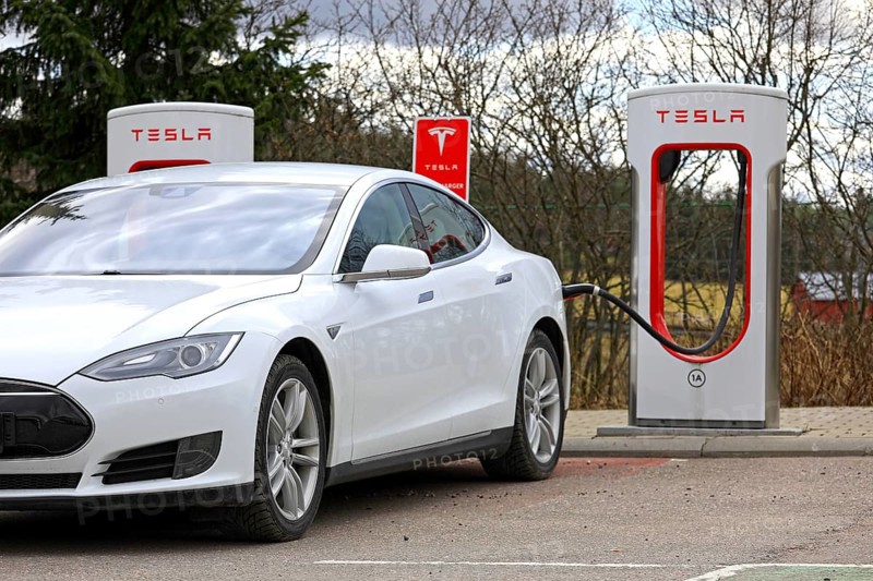 White Tesla Model S electric car connected and charging at Supercharger station on a day of spring in Paimio, Finland, April 28, 2018, Europe
