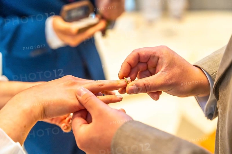 A man and woman are getting married and the man is putting a ring on the woman's finger