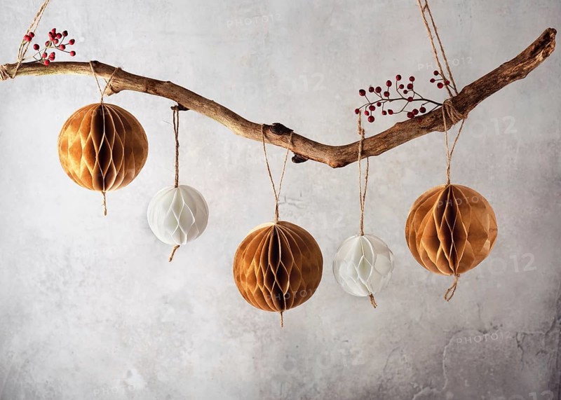 Handmade honeycomb balls hanging on a tree branch as a beautiful Christmas decoration. Scandinavian paper handicraft concept