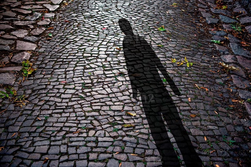 Human shadow on cobblestones at night, symbolic photo crime, burglar, creepy
