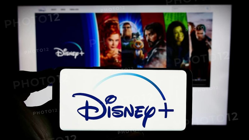 Stuttgart, Germany, 11-14-2023: Person holding cellphone with logo of US video-on-demand streaming service Disney Plus in front of business webpage. Focus on phone display, Europe
