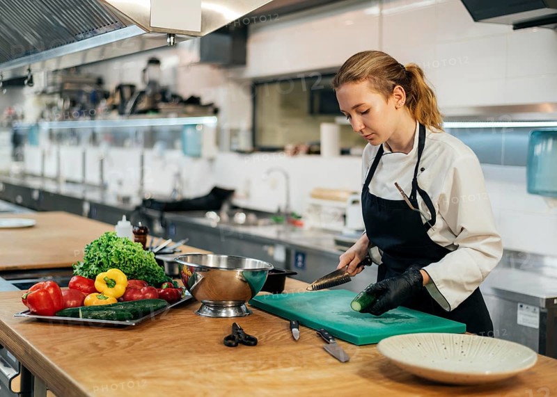 Side view female chef kitchen slicing vegetables