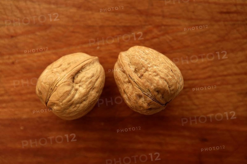 Two walnuts on a golden wood aged table