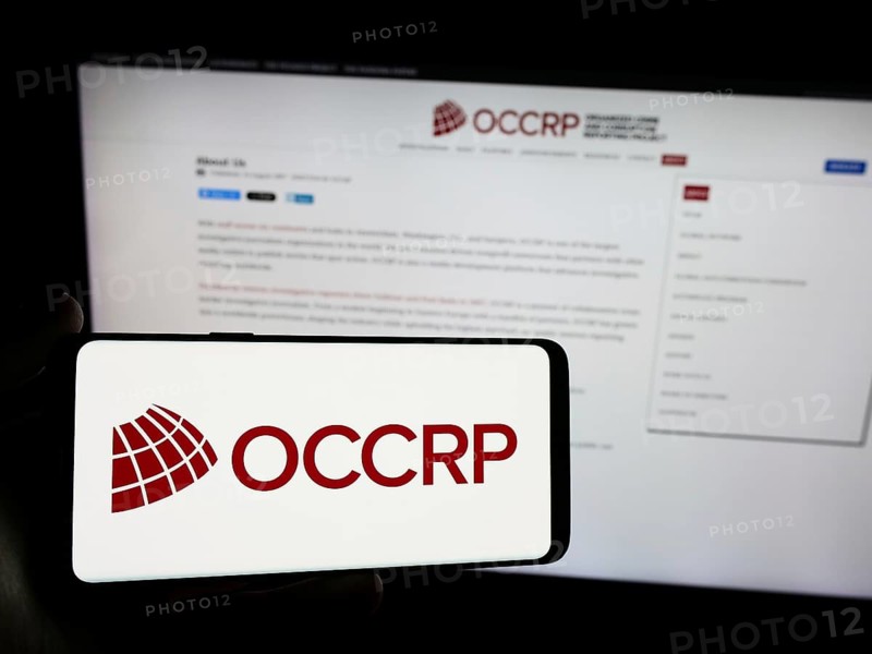 Stuttgart, Germany, 05-22-2024: Person holding smartphone with logo of Organized Crime and Corruption Reporting Project (OCCRP) in front of website. Focus on phone display, Europe