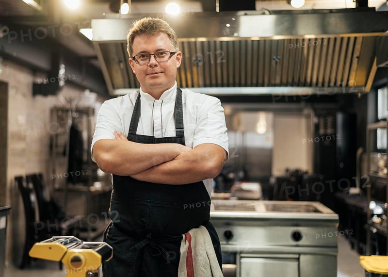 Front view male chef posing with arms crossed kitchen