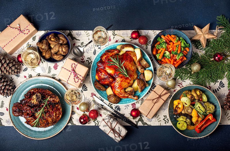 Christmas evening table top view with festive food and sparkling wine glasses, Xmas dinner with assorted delicious meals, wrapped presents and fir tree flat lay