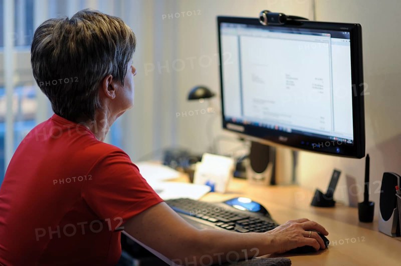 A woman sits at a desk and works on a PC