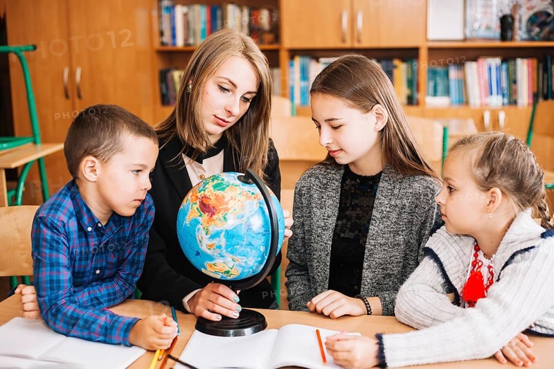 Young woman teaching geography pupil with globe