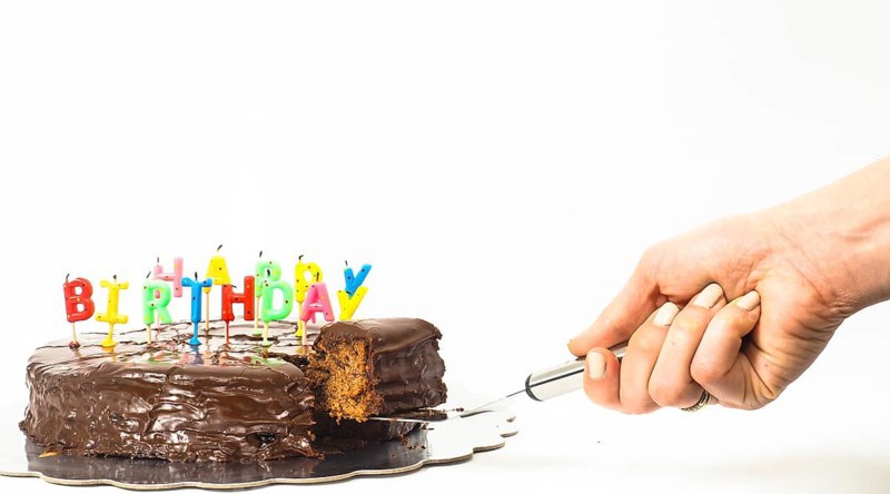 Female person serving a homemade sacher chocolate cake with birthday candles