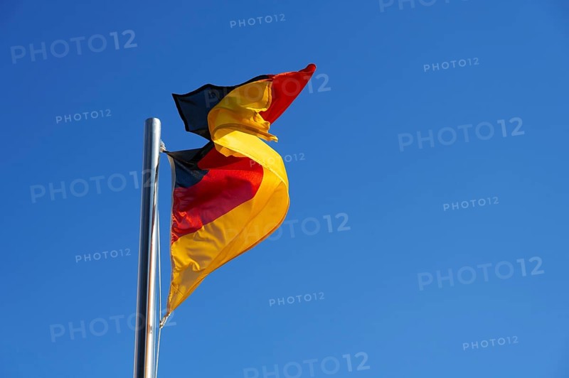 German flag, national flag in strong wind against blue sky