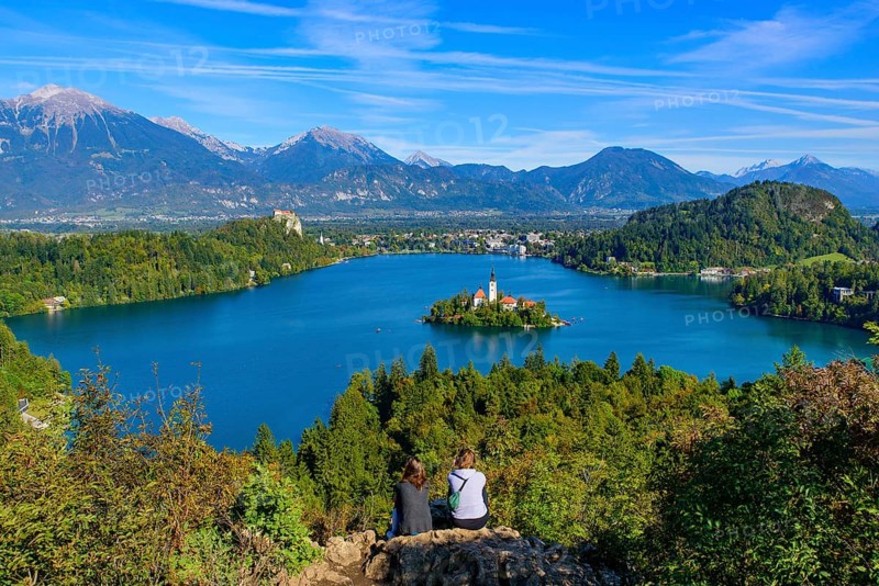 Two people at Osojnica Hill watching the view of Bled Island and Lake Bled, a popular tourist destination in Slovenia