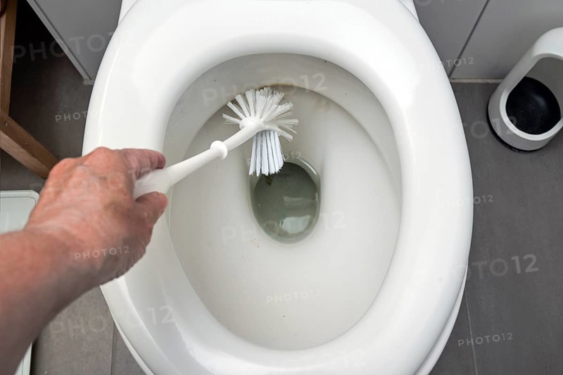 Hand is cleaning a disgusting dirty toilet with a brush, hygiene for health in the household, copy space, selected focus, narrow depth of field