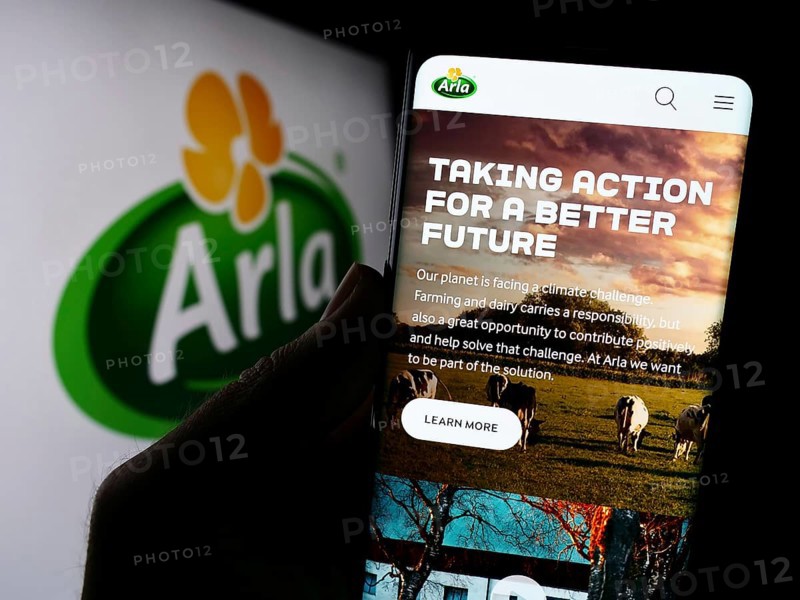 Stuttgart, Germany, 09-08-2023: Person holding cellphone with webpage of Nordic dairy company Arla Foods amba on screen in front of logo. Focus on center of phone display, Europe