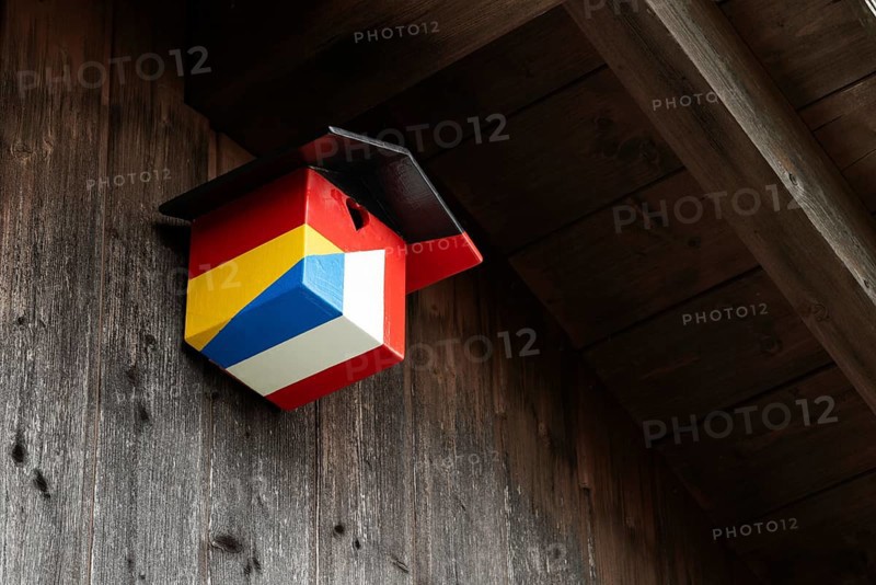 A nesting box for birds, songbirds, titmouse, sparrow, sparrow in the colours of the German and French national flags hangs on a house wall, German-French relations, friendship