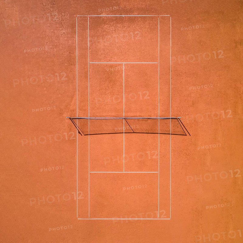 Aerial view of a single red clay tennis court without players