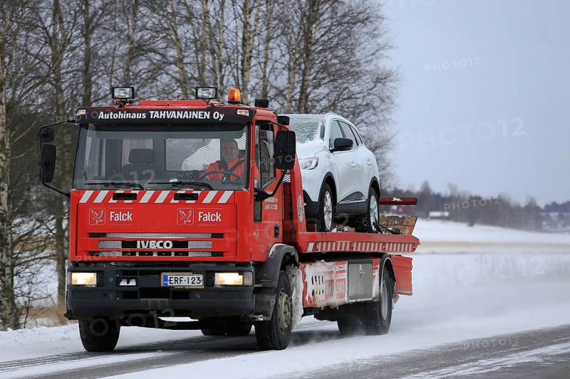 SALO, FINLAND, JANUARY 7, 2017: Red Iveco tow truck tows a car along road on a cold day in winter. The subzero temperatures can cause many mechanical failures of motor vehicles