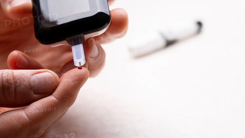 Pierced caucasian finger ready to measure glucose level by glucose meter closeup view with copy-space. Diabetes awareness concept