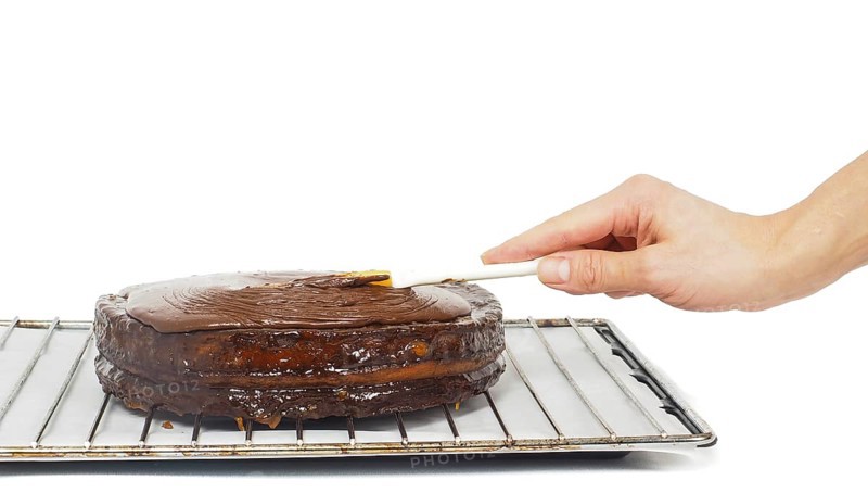 Pastry chef making final touches to a sacher chocolate cake with icing