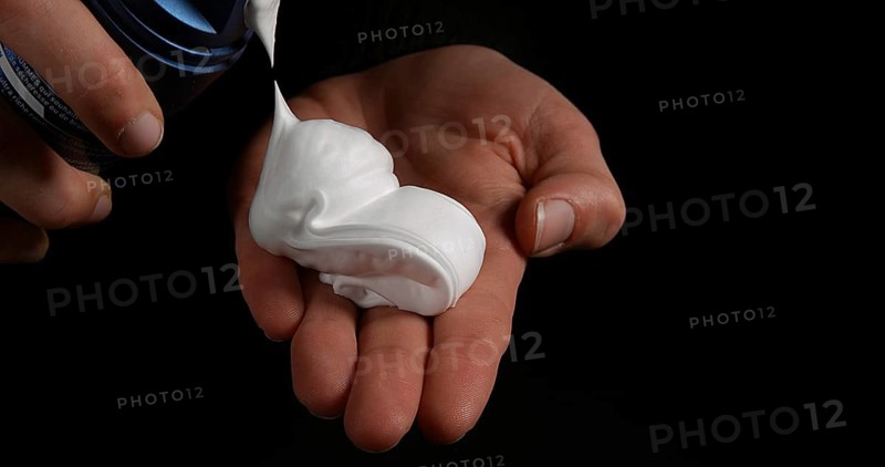 Hand of Woman and shaving foam against Black Background