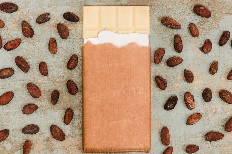 Scattered cocoa beans with white chocolate bar grunge background