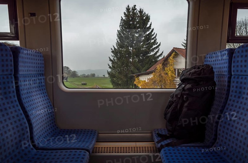 German train interior with a rucksack on the seats and a bavarian landscape view on the window