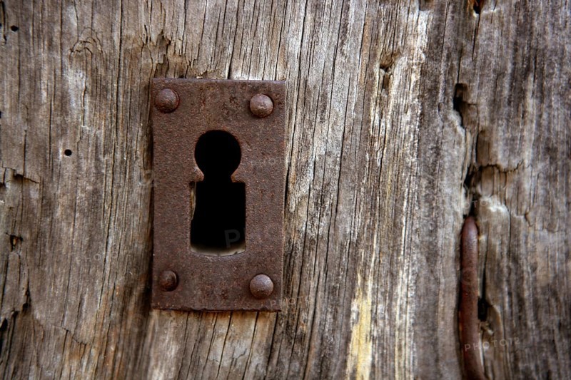 Key hole over aged gray old wood, rusty metal