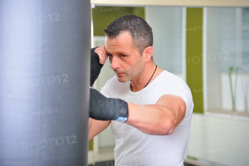 Boxers trained on a punching bag. Man trains on a punching bag