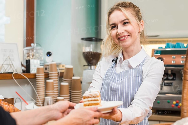 Smiling female baker serving pastry cake customer