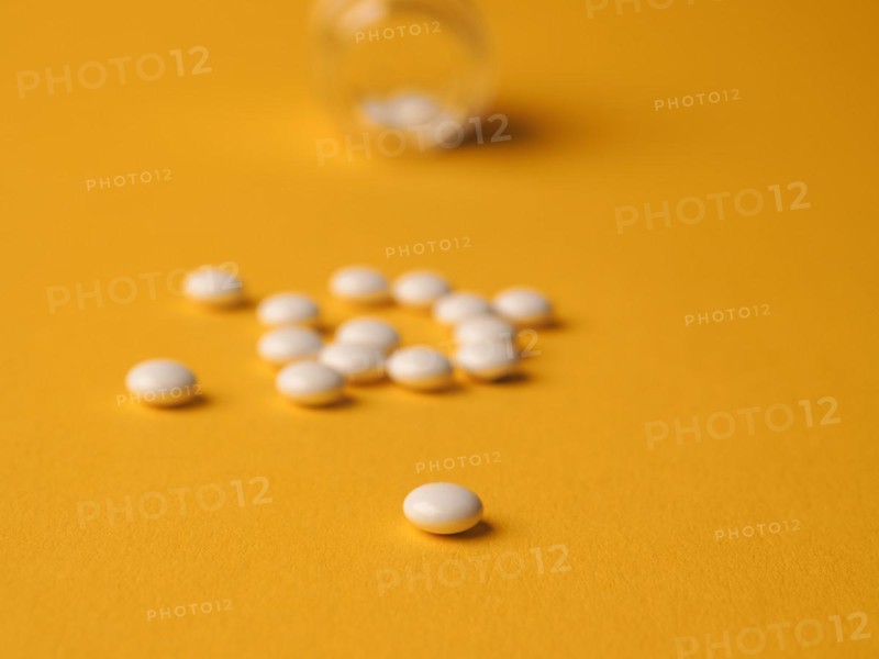 White pills on a yellow background, food supplements, vitamin pills, health care concept