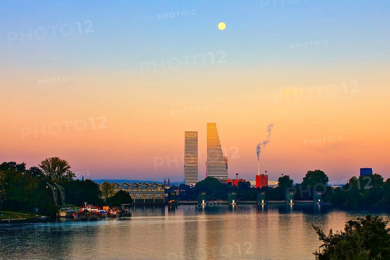 River landscape at sunset with skyscrapers and full moon. The scene contains natural and industrial accents, Roche Towers, Hoffmann- la Roche, tallest building in Switzerland, Basel, Canton Baselstadt, Switzerland, Europe