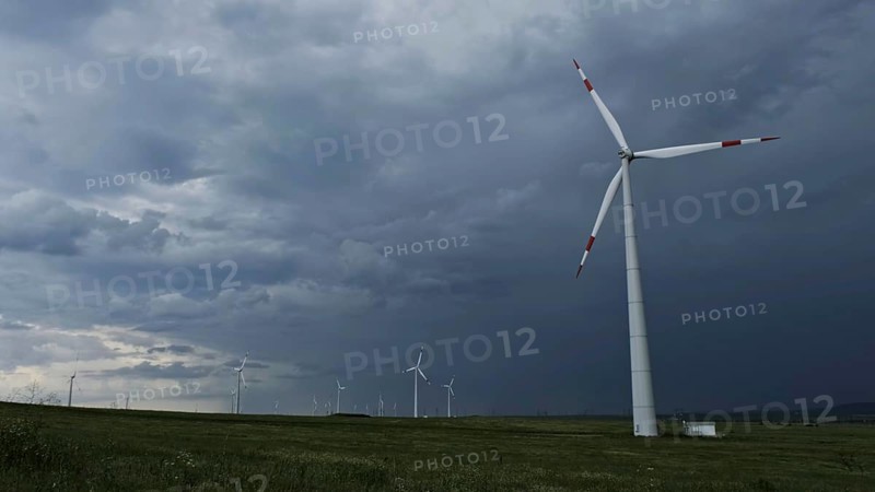 Windmill or wind turbine in rotation to generate electricity energy against the backdrop of a storm clouds sky