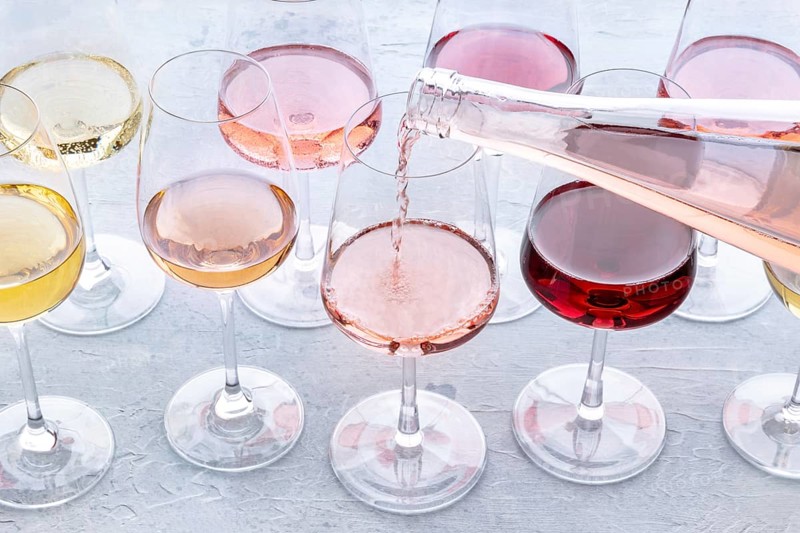 Rose wine pour into a glass at a tasting. Rose, red, and white wine, drinks on a table at a winery. An assortment of wines of many different colours, Food photography, Food photography
