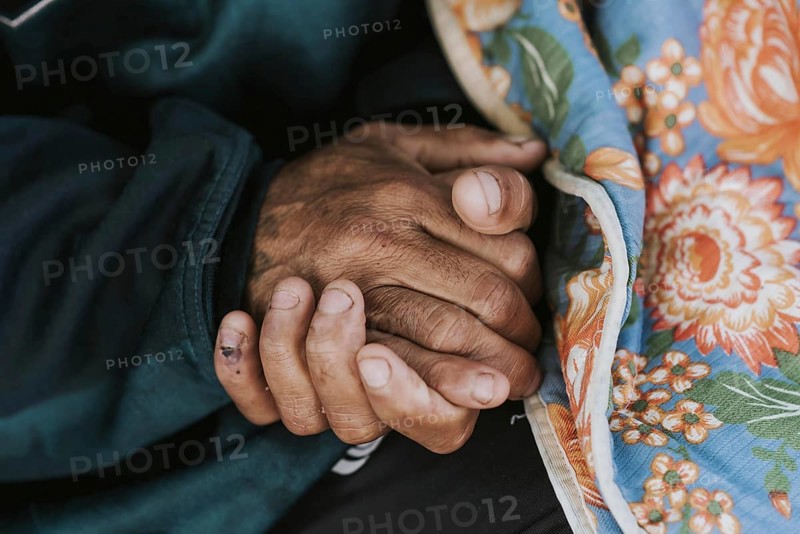 Homeless man holding his hands with blanket
