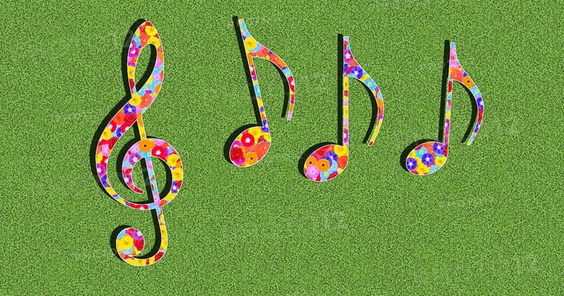 Graphic with clef and notes as a symbol for music with colourful flowers on a green background in sunlight with drop shadow