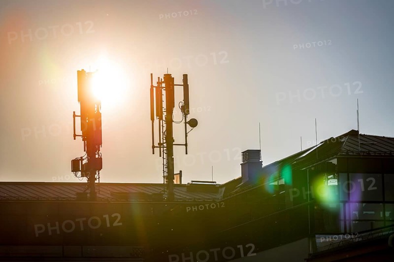 Silhouette of communication or cell tower on the rooftop of a building, evening sunshine