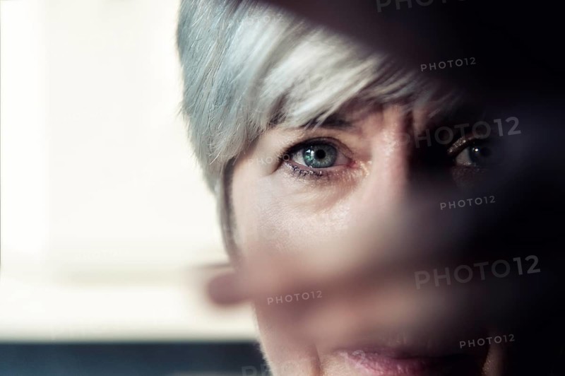 A woman looks through the fingers of her hand
