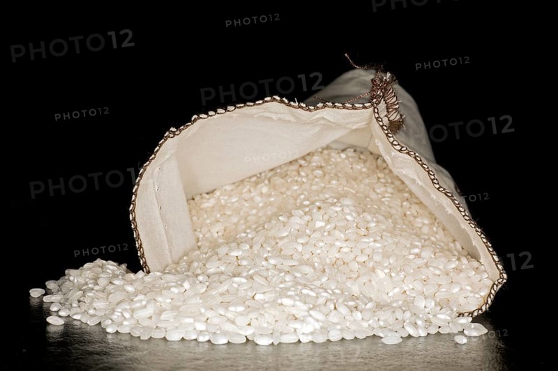 Spanish paella rice, of the Bomba variety, in a cotton bag, food photography with black background