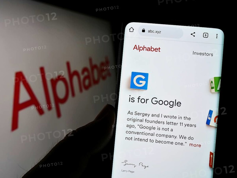 Stuttgart, Germany, 10-30-2022: Person holding cellphone with webpage of US holding company Alphabet Inc. (Google) on screen in front of logo. Focus on center of phone display, Europe
