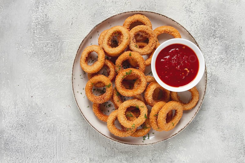 Deep fried onion rings, appetizer, with tomato sauce, on a light background, no people, favorite dish