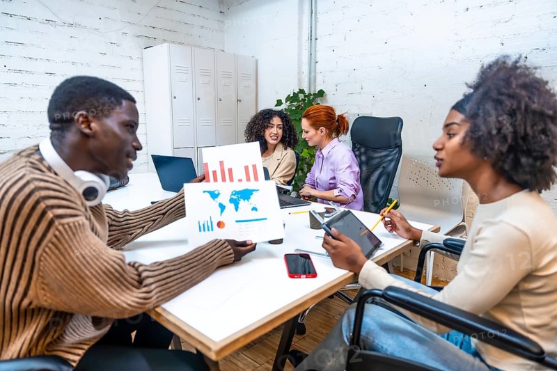 African man showing data to a disabled colleague in a modern and new coworking room