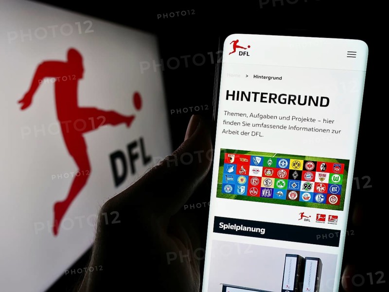 Stuttgart, Germany, 12-07-2023: Person holding cellphone with webpage of German football company DFL Deutsche Fußball Liga GmbH with logo. Focus on centre of phone display, Europe