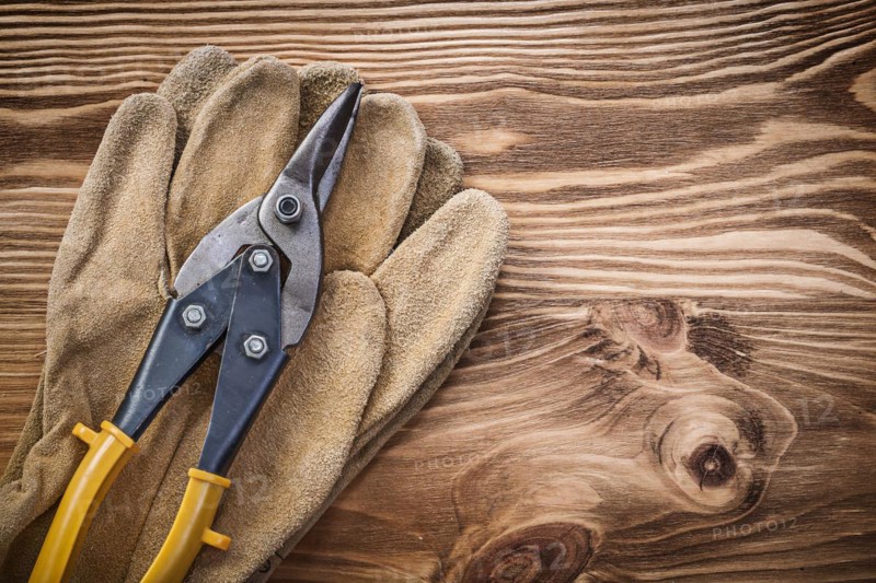 Leather protective gloves Pewter scissors on wooden board Construction concept