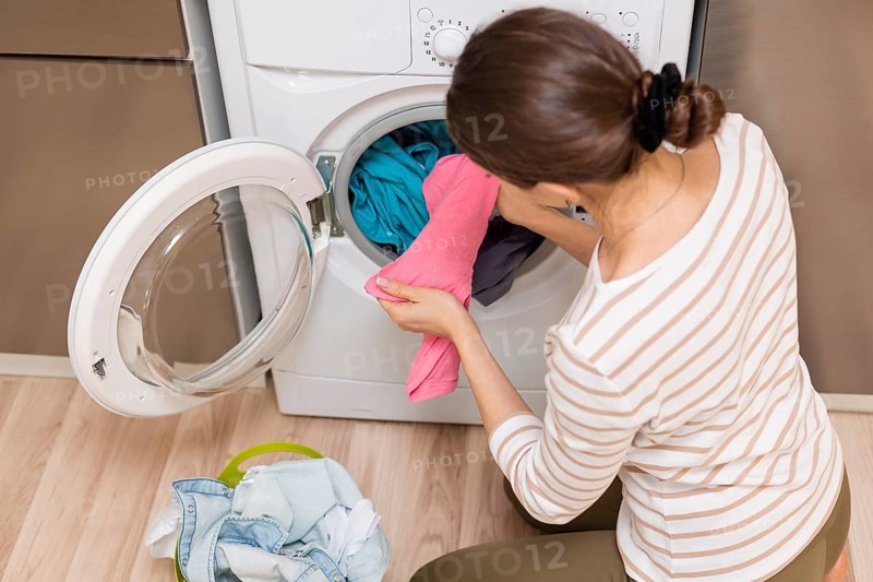 Lady taking clothes out washing machine. High resolution photo